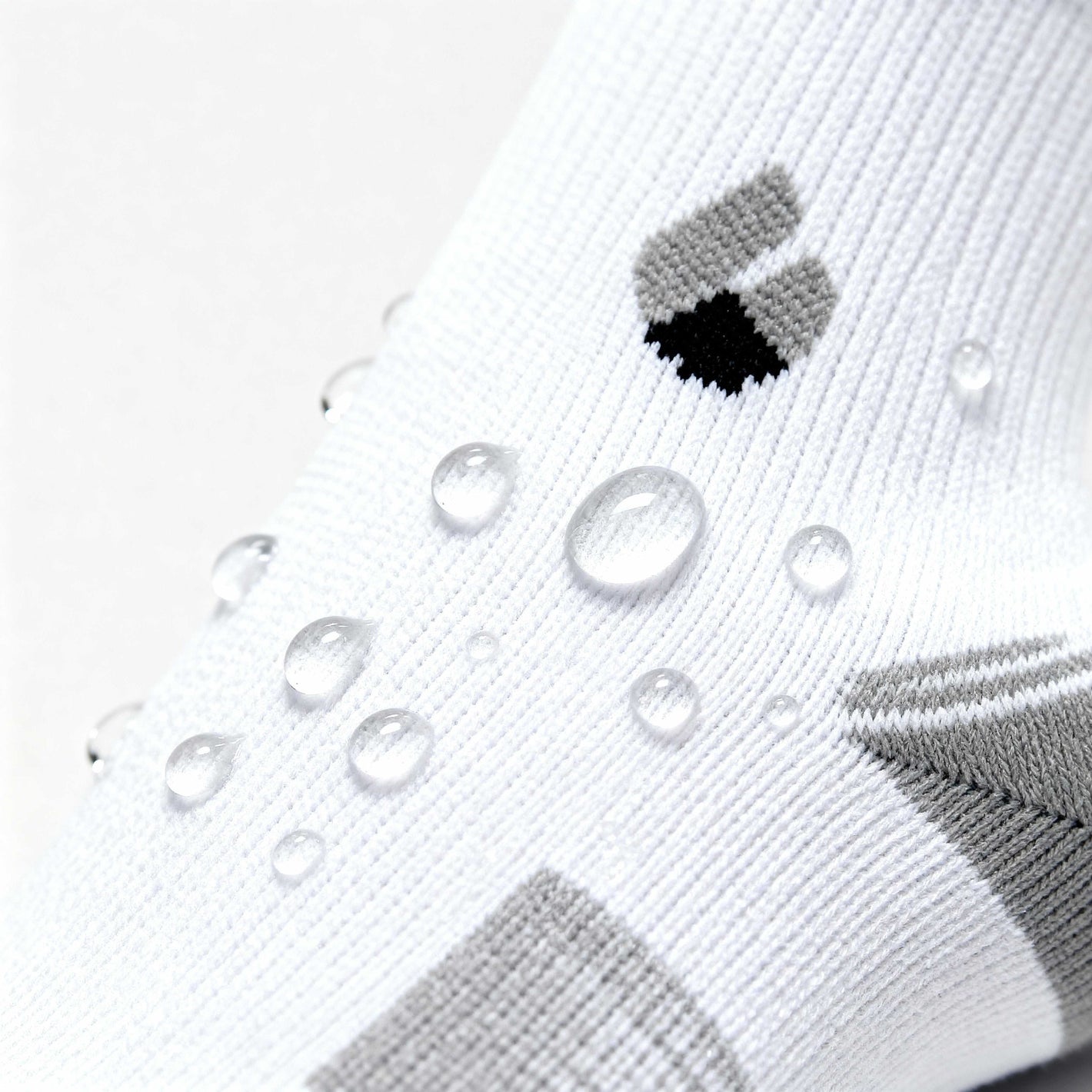 white and grey ankle running socks with water droplets showing moisture-wicking fabric detail